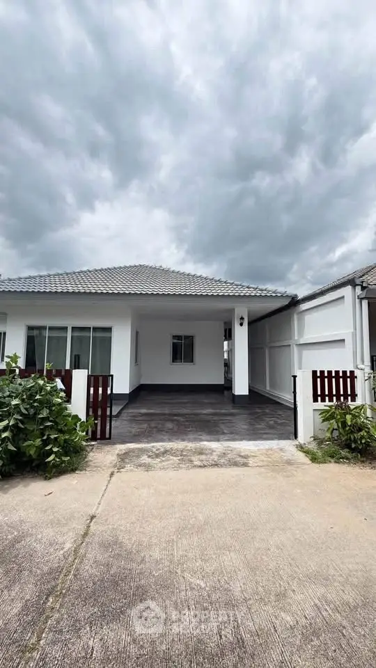 Charming single-story home with modern design and spacious driveway under a cloudy sky.