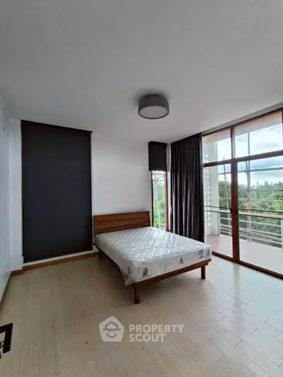 Spacious bedroom with large windows and balcony access in modern apartment.
