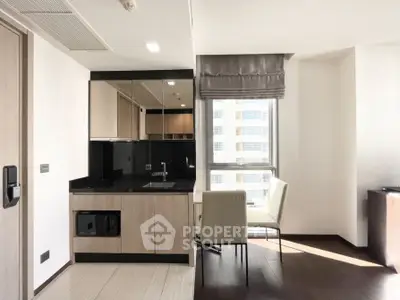 Modern kitchen with sleek cabinetry and dining area in bright apartment