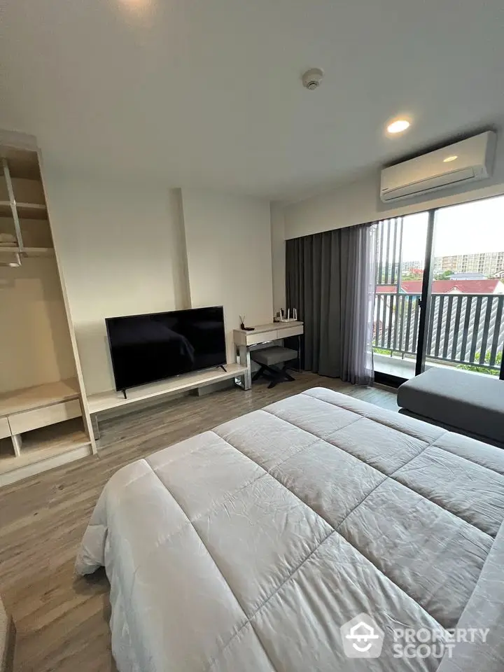 Modern bedroom with balcony view, featuring sleek TV and air conditioning