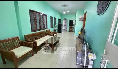 Spacious living room with green walls and wooden furniture, ideal for family gatherings.