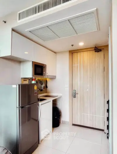 Modern compact kitchen with sleek appliances and stylish cabinetry in a contemporary apartment.