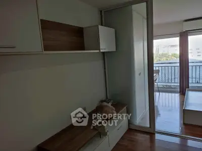 Modern apartment interior with balcony view, featuring sleek built-in storage and natural light.