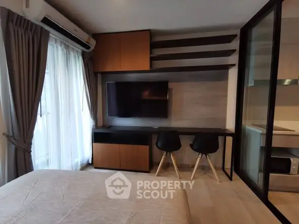 Modern bedroom with stylish TV setup and cozy workspace