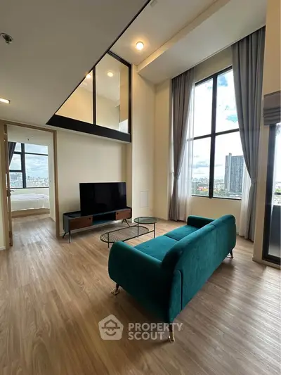 Spacious modern living room with high ceilings and large windows offering city views.