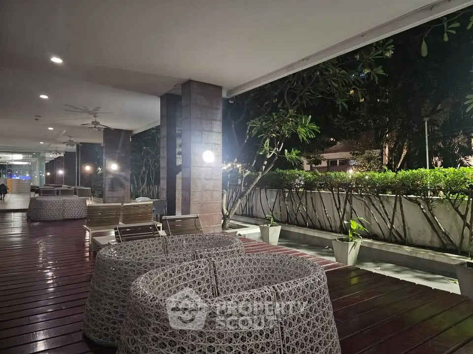 Elegant outdoor seating area with modern wicker furniture and lush greenery at night.