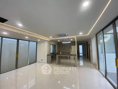 Spacious modern living room with open kitchen and large windows, perfect for natural light and contemporary living.