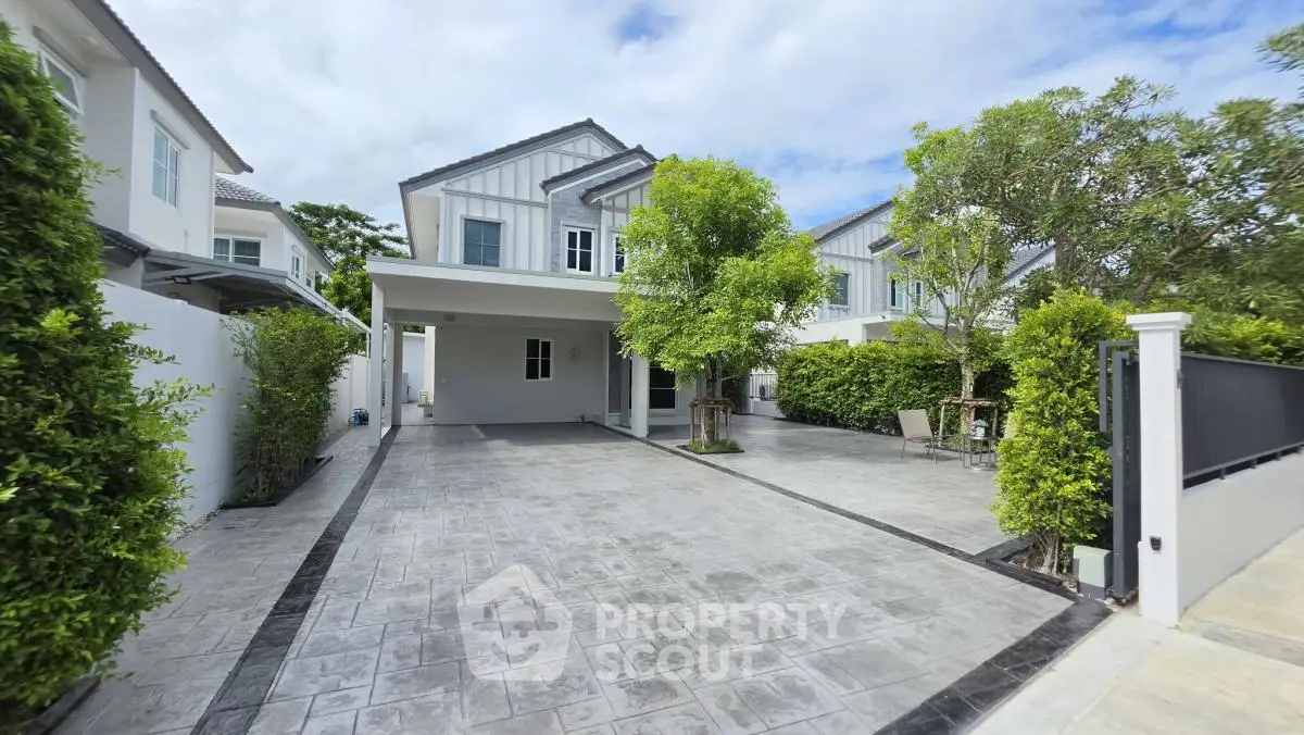 Modern two-story house with spacious driveway and lush greenery