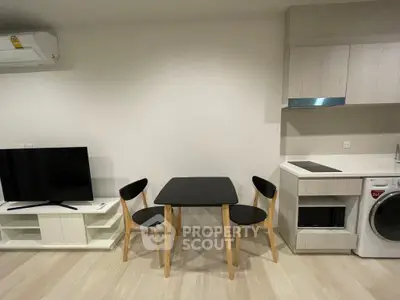 Modern studio apartment with sleek furniture and compact kitchen appliances.