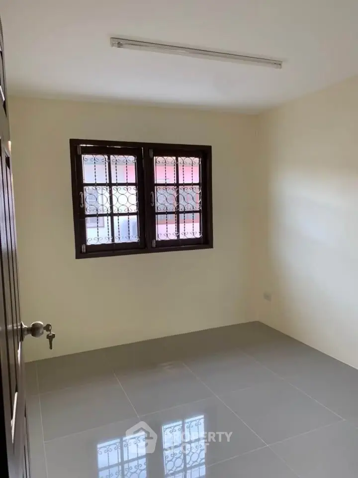 Spacious unfurnished room with tiled flooring and window view, perfect for customization.