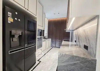 Modern kitchen with sleek black fridge and marble countertops in a stylish apartment.