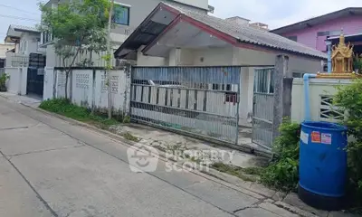 Charming suburban house with gated entrance and lush greenery, perfect for family living.
