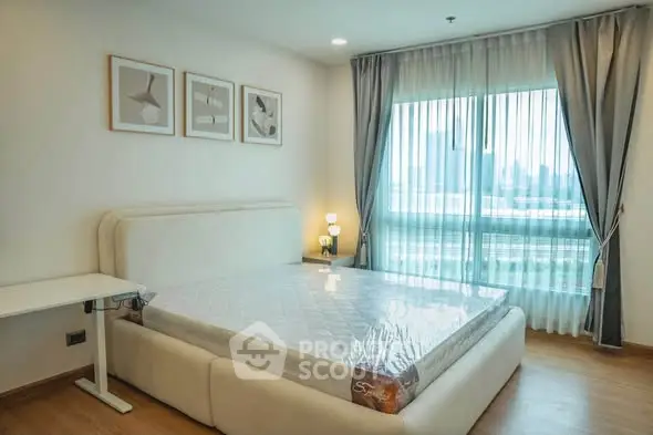 Spacious bedroom with large window and modern decor in a high-rise apartment.