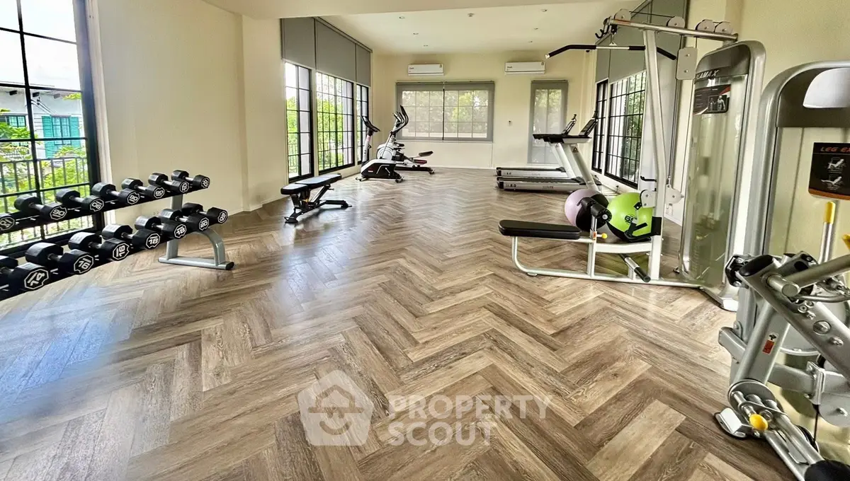 Spacious home gym with modern equipment and large windows for natural light.