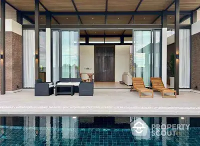 Luxurious modern villa with poolside view and elegant outdoor seating area.