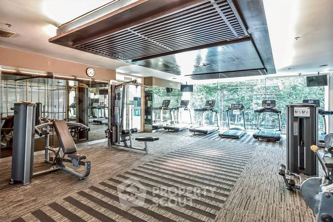 Spacious modern gym with state-of-the-art equipment and large windows for natural light.