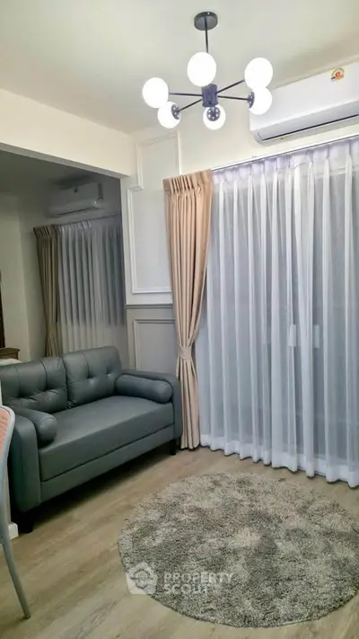 Cozy living room with modern decor, featuring a stylish gray sofa, elegant curtains, and a chic chandelier.
