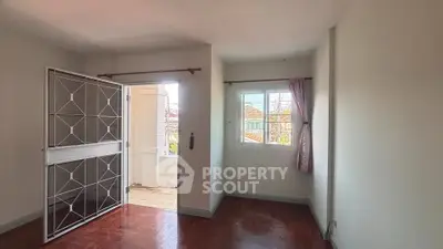 Bright room with wooden flooring and large window, perfect for a cozy living space.