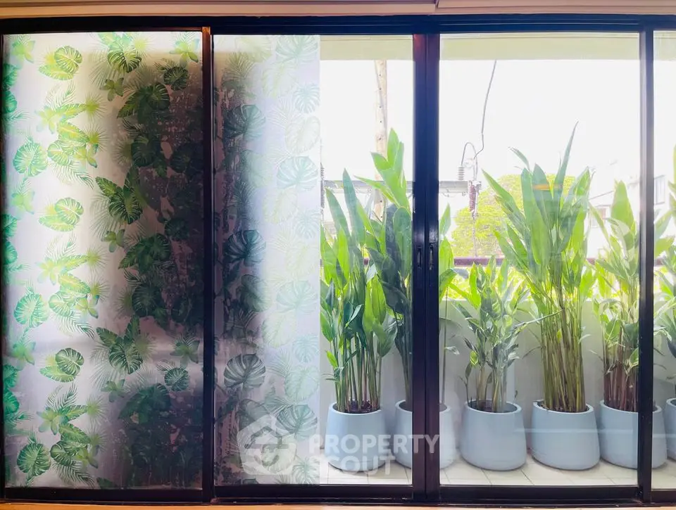 Charming balcony with lush potted plants and sliding glass doors for natural light.