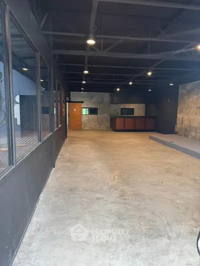 Spacious industrial-style interior with concrete floors and exposed ceiling beams, ideal for creative workspace.