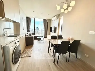Modern open-plan living room with kitchen and dining area, featuring city view and stylish lighting.