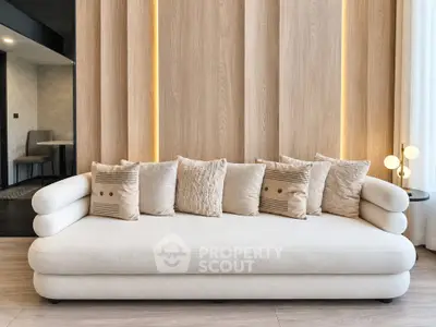 Elegant modern living room with stylish beige sofa and decorative pillows, featuring warm wooden paneling and ambient lighting.