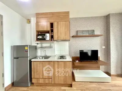 Modern compact kitchen with wooden cabinetry and integrated appliances in cozy apartment.