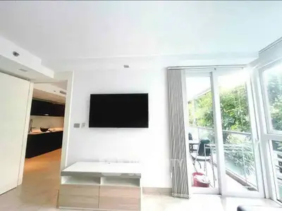 Modern living room with wall-mounted TV and balcony view in a stylish apartment.