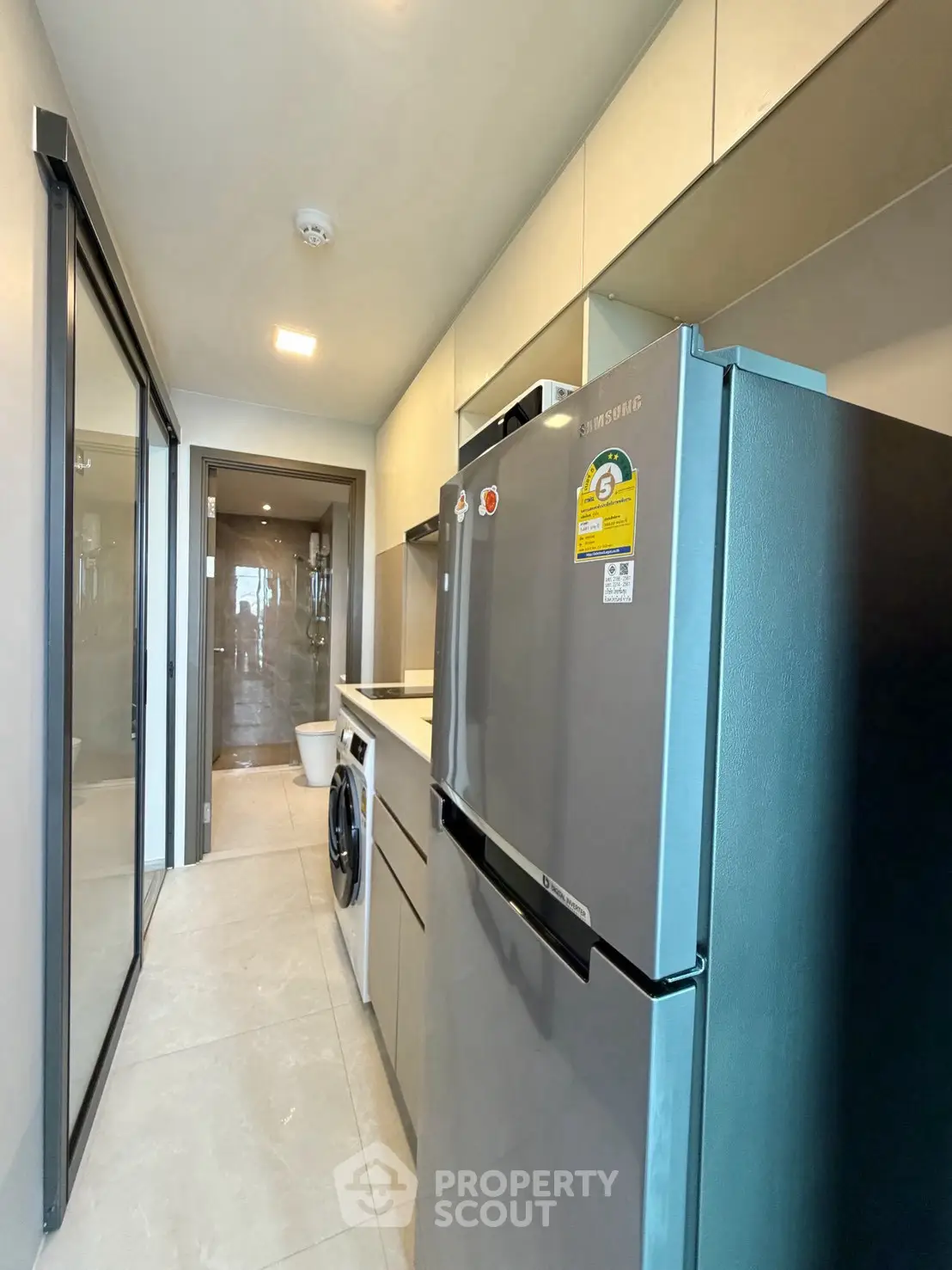 Modern kitchen with sleek appliances and washing machine in compact layout