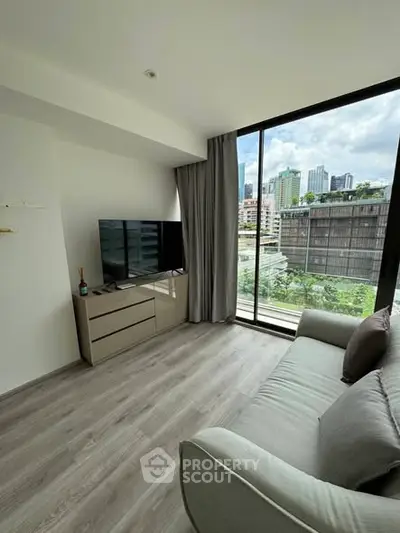 Modern living room with large window and city view, featuring sleek furniture and stylish decor.