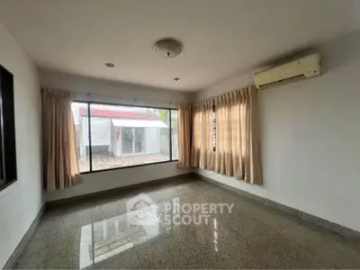 Spacious empty room with large windows and air conditioning unit