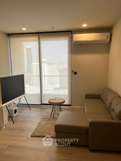 Modern living room with city view, featuring a cozy sofa and large TV, perfect for relaxation.