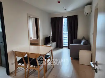 Modern living room with dining area and city view, featuring sleek furniture and natural light.