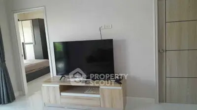 Modern living room with sleek TV setup and view into cozy bedroom.