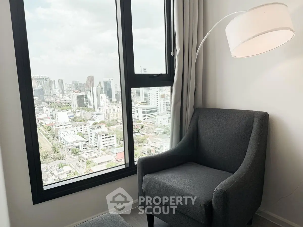 Modern living room with city view from large window and stylish armchair.