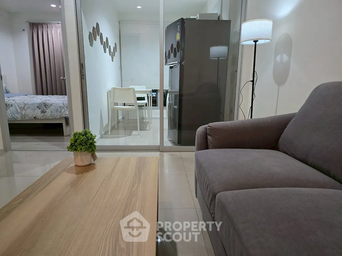 Modern living room with cozy sofa and stylish decor, open view to dining area and bedroom.