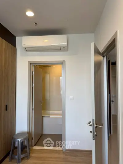 Modern interior with air conditioning and wooden flooring, featuring a bathroom entrance.