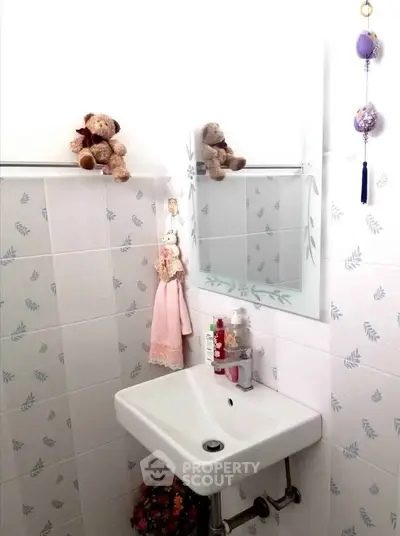 Charming bathroom with decorative tiles and modern sink, perfect for cozy living spaces.