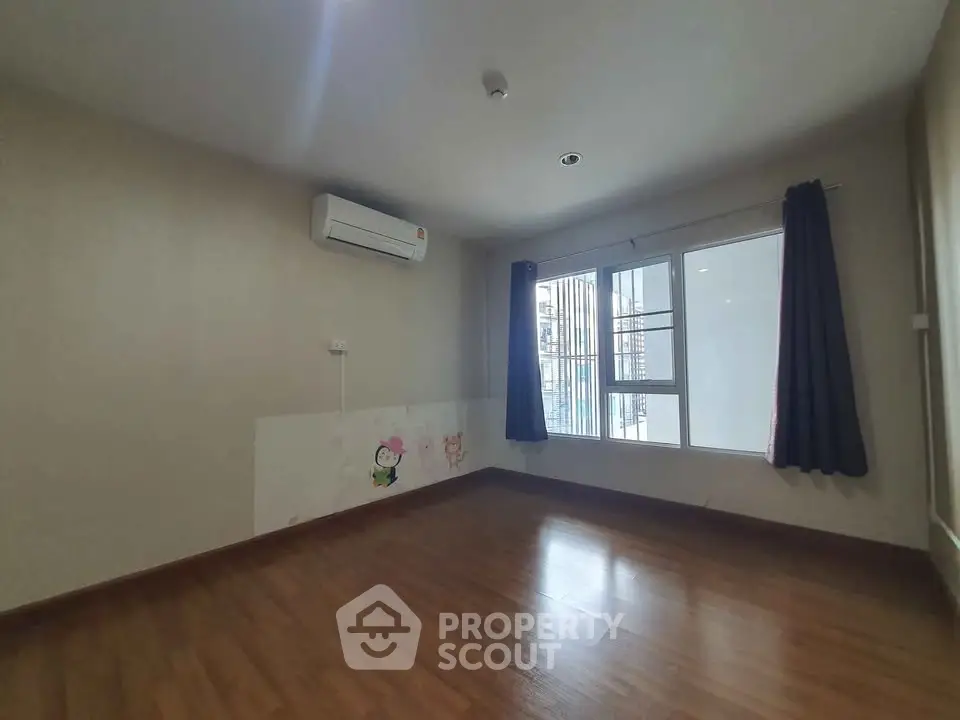 Spacious empty room with wooden flooring and large window, ideal for customization.