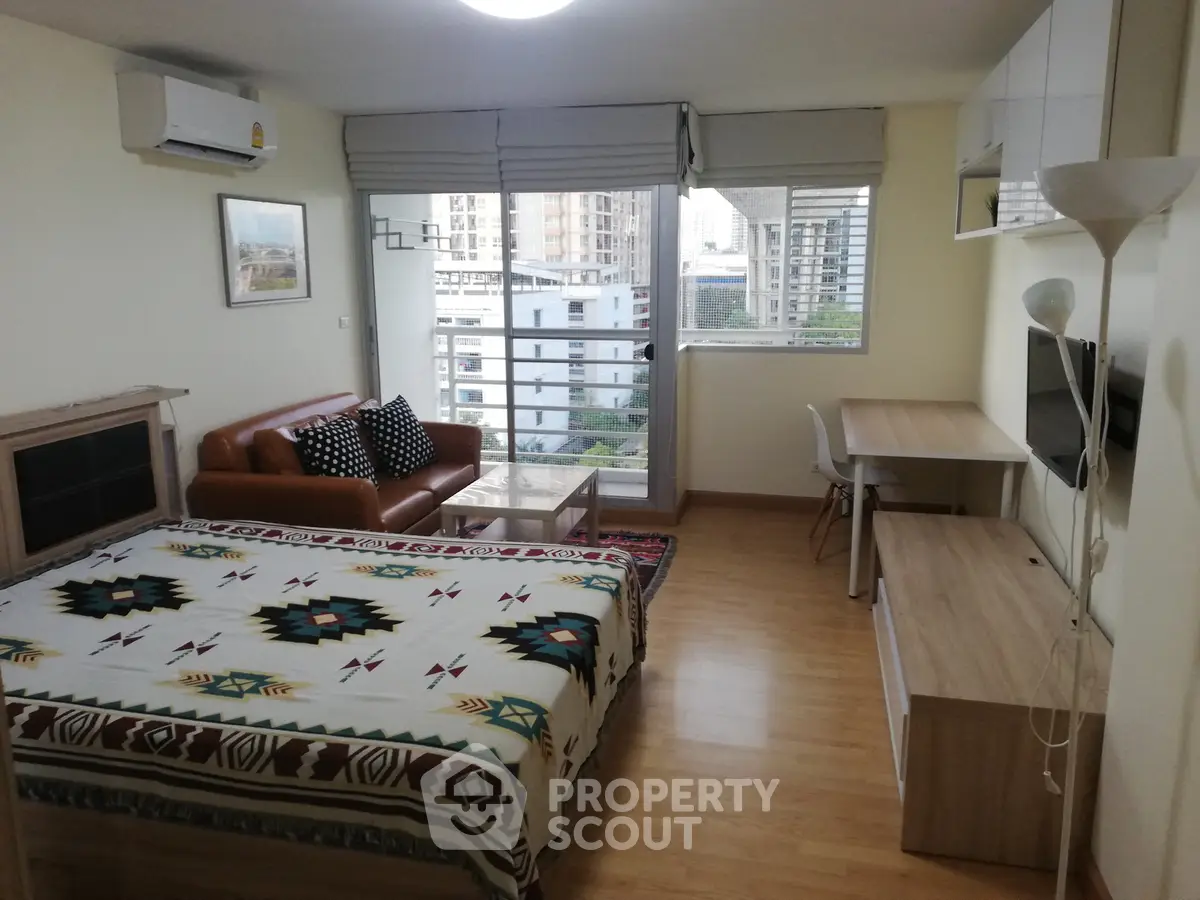 Modern studio apartment with cozy living area and city view, featuring stylish decor and ample natural light.