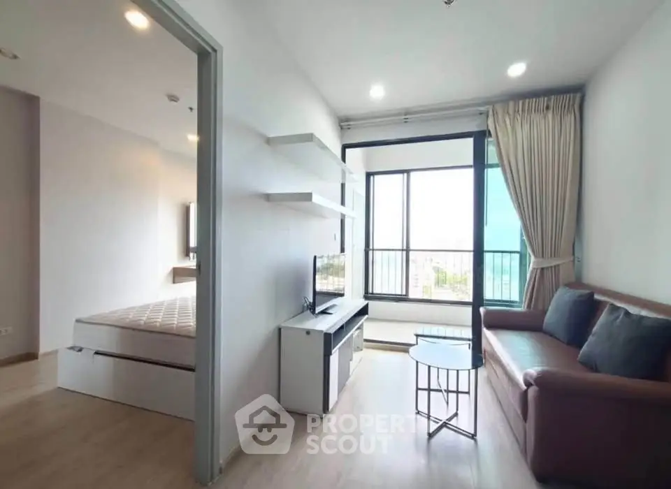 Modern apartment with cozy living room and bedroom, featuring large windows and stylish furnishings.