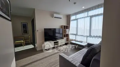 Modern living room with large windows, sleek furniture, and abundant natural light in a stylish apartment.