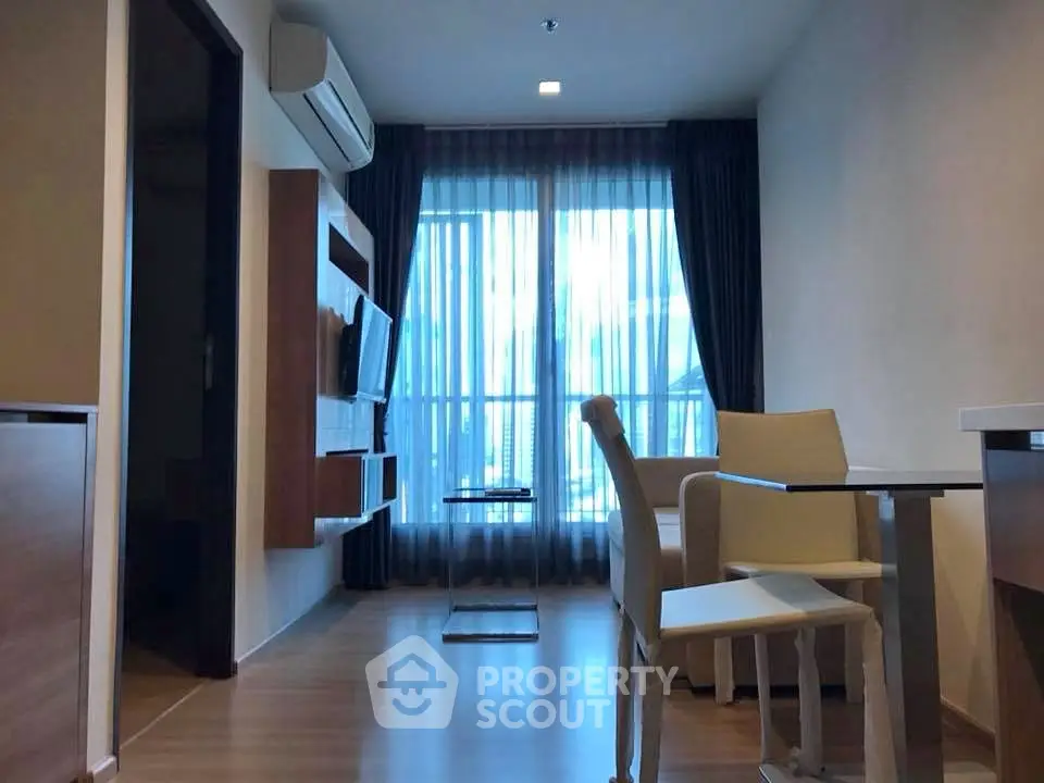 Modern living room with sleek furniture and large window offering natural light.