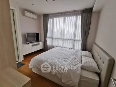 Cozy bedroom with large window and modern furnishings in a stylish apartment.