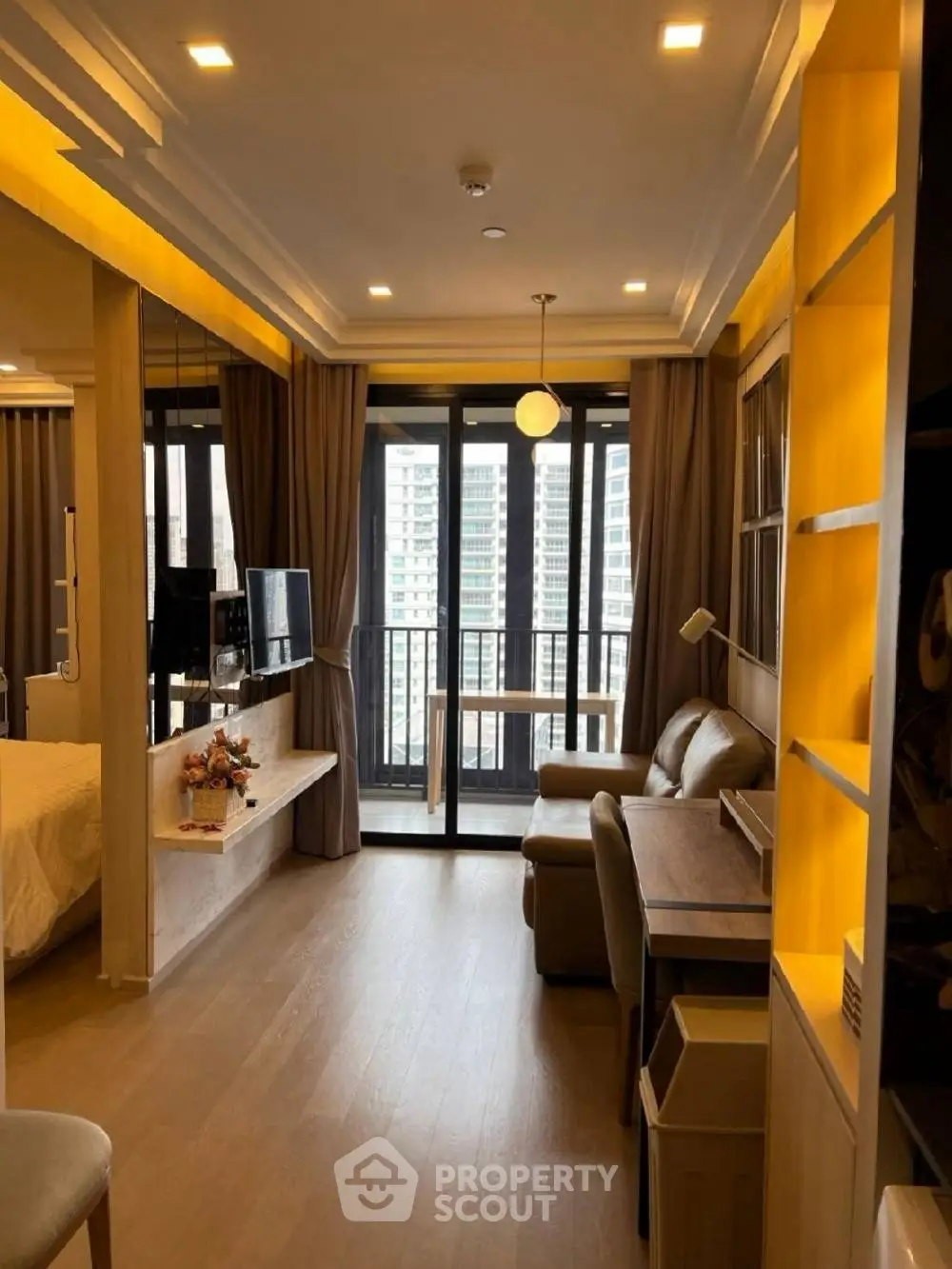 Modern living room with balcony view, cozy seating, and stylish lighting in a high-rise apartment.