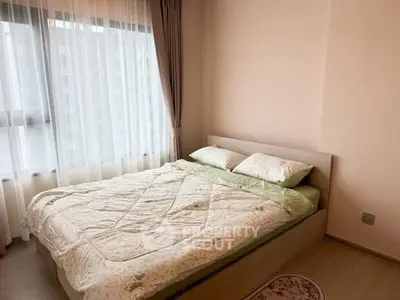 Cozy bedroom with large window and elegant curtains, perfect for relaxation.