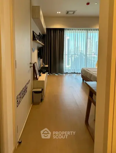 Spacious living room with modern decor and large window offering city views.