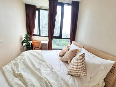 Cozy bedroom with large windows and city view, featuring stylish decor and comfortable bedding.
