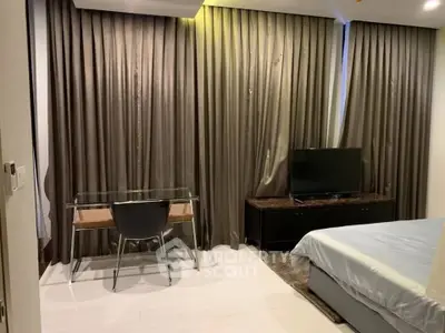 Modern bedroom with sleek desk and TV, featuring elegant floor-to-ceiling curtains.