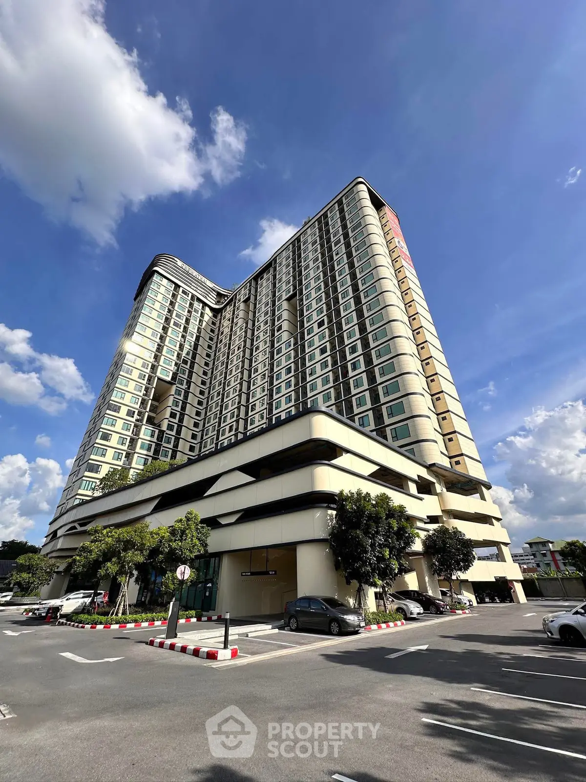 Stunning high-rise building with modern architecture and ample parking, set against a clear blue sky.